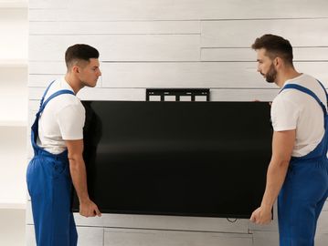 Two movers carrying a large flat-screen TV.