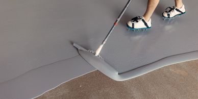 Person spreading gray epoxy flooring.