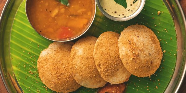 South Indian meal with idlis, sambar, and chutney on a banana leaf.