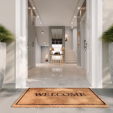 Modern entrance with welcome mat and marble planters on tiled floor.