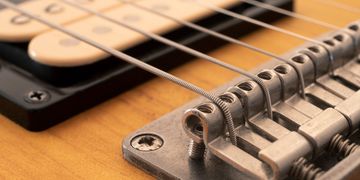 Close-up of electric guitar strings and bridge.