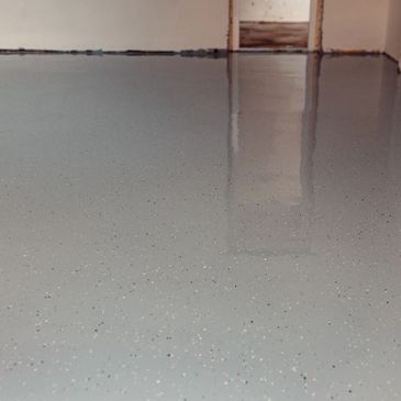 Smooth gray epoxy-coated floor reflecting light in an indoor space.