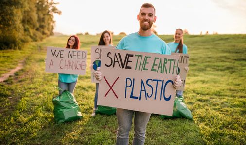 Group of volunteers holding signs advocating to save the earth and reduce plastic use.