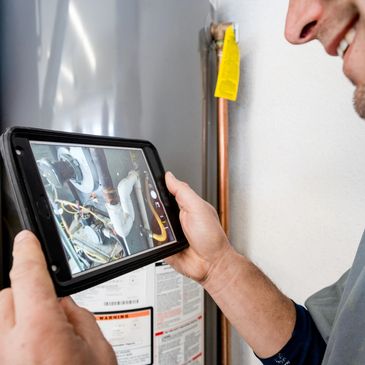 Technician using tablet to inspect furnace components.