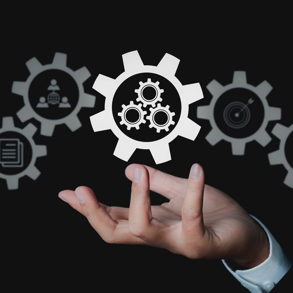 Hand interacting with digital gears symbolizing business and technology integration.