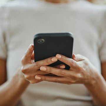 Person holding a smartphone with neatly manicured nails.