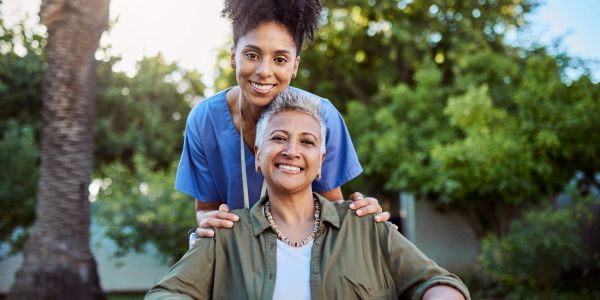 Smiling woman and caregiver outdoors.