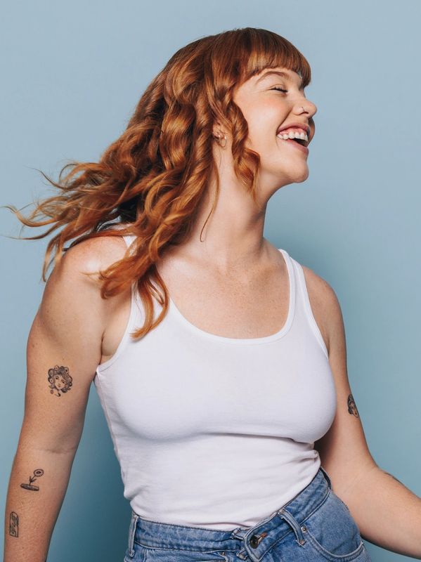 Happy woman with tattoos smiling against blue background.