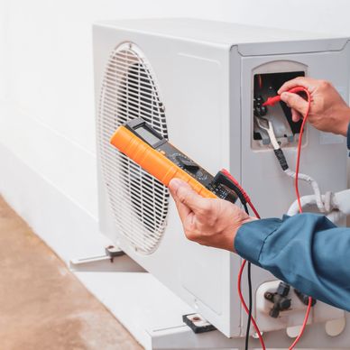Technician using a multimeter to check an air conditioning unit.