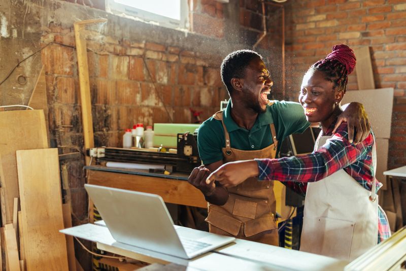 Two happy excited fan friends in euphoria mood after winning in a bet with a laptop.