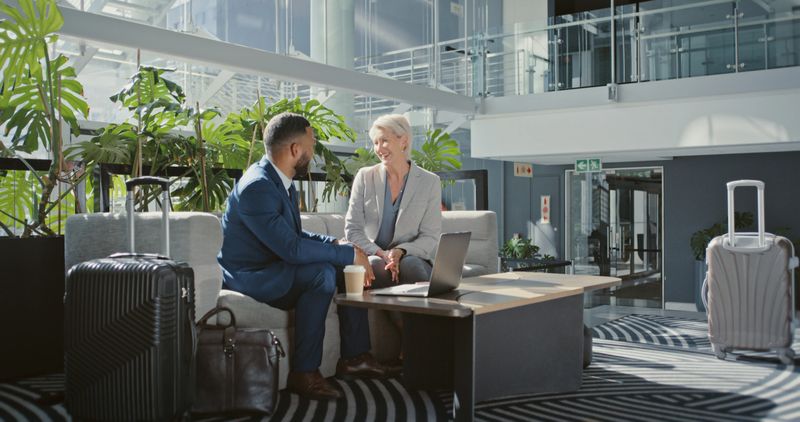 Business meeting, travel and people in lobby for collaboration, global b2b conversation and international opportunity with laptop and coffee. Diversity, onboarding and hiring manager career talking