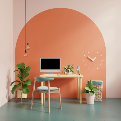 Modern minimalist workspace with orange accent wall and plants.