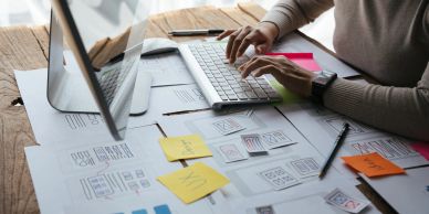 Person working on a computer with sketches and notes.