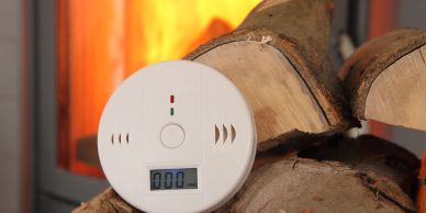 Smoke detector near a fireplace with burning firewood.