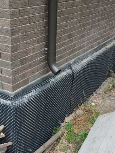 Foundation drainage system with protective membrane and downspout.