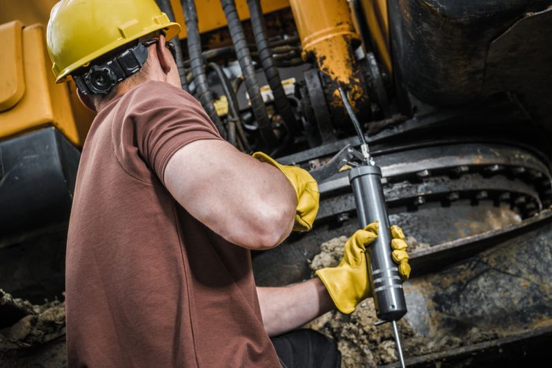 Caucasian Construction Worker Performing Excavator Maintenance.