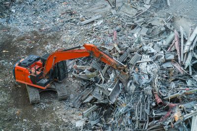 Orange excavator clearing debris at a demolition site.