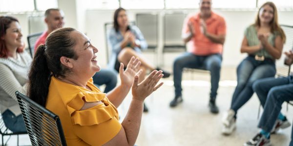Grupo de personas en círculo aplaudiendo y sonriendo.