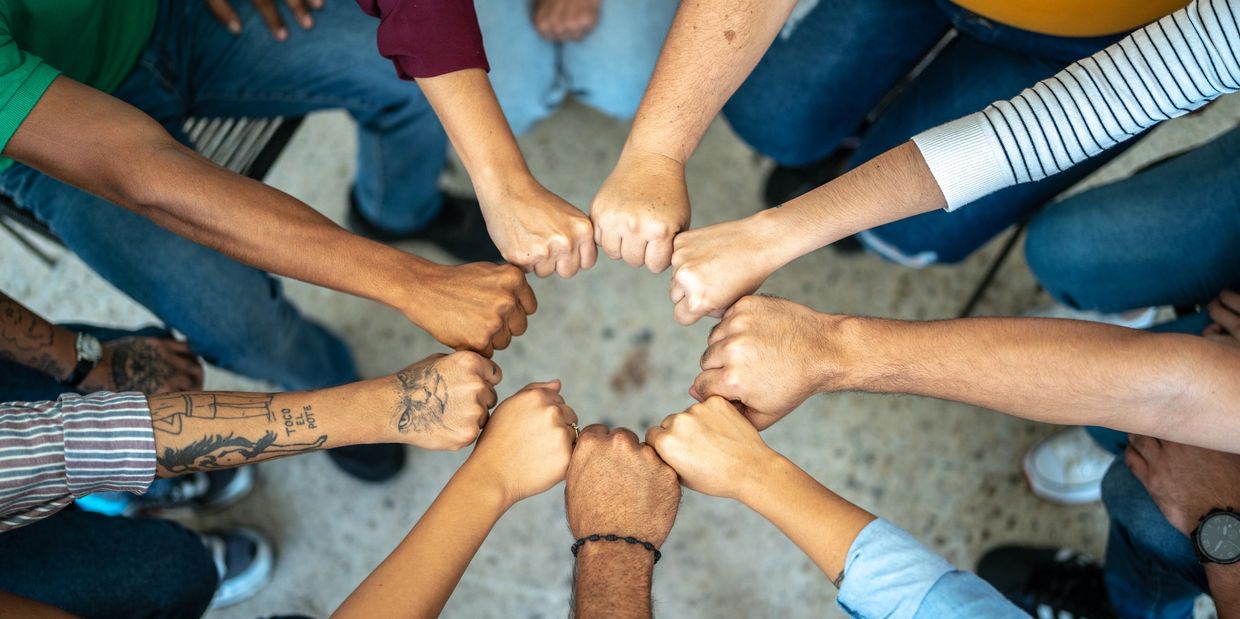 Group of diverse people doing a fist bump in a circle.