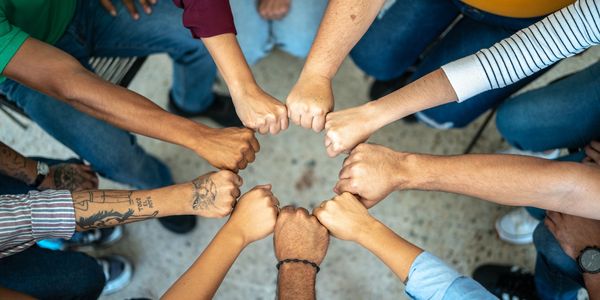 Group of diverse people joining fists in unity and teamwork.