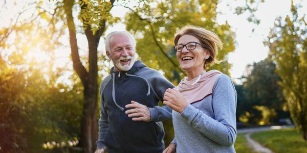 Happy elderly couple jogging outdoors on a sunny day.