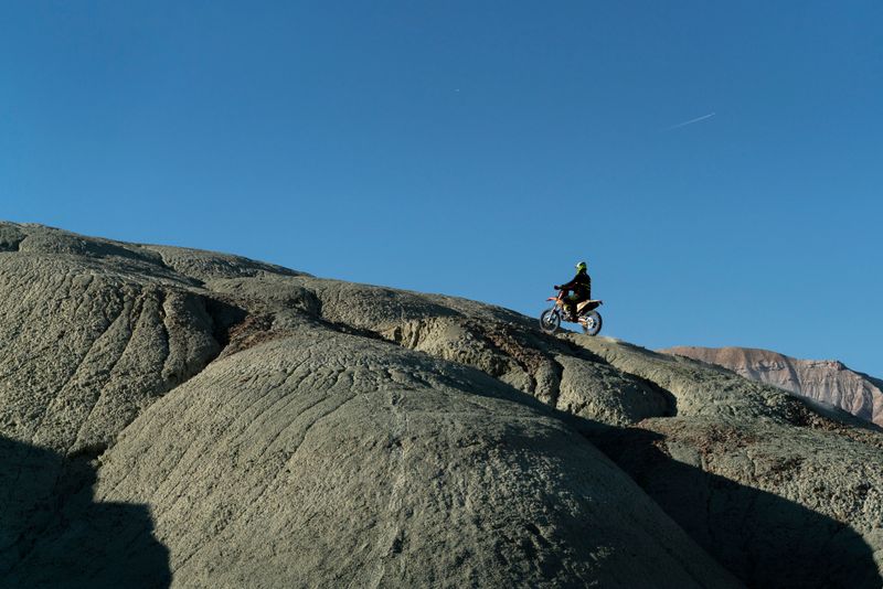 A speed race with cross bikes on an obstacle course on rough dirt terrain. The motor driver is climbing the hill over rough terrain. Shot with a full frame camera.