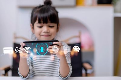 A girl uses a smartphone with digital security icons floating above.
