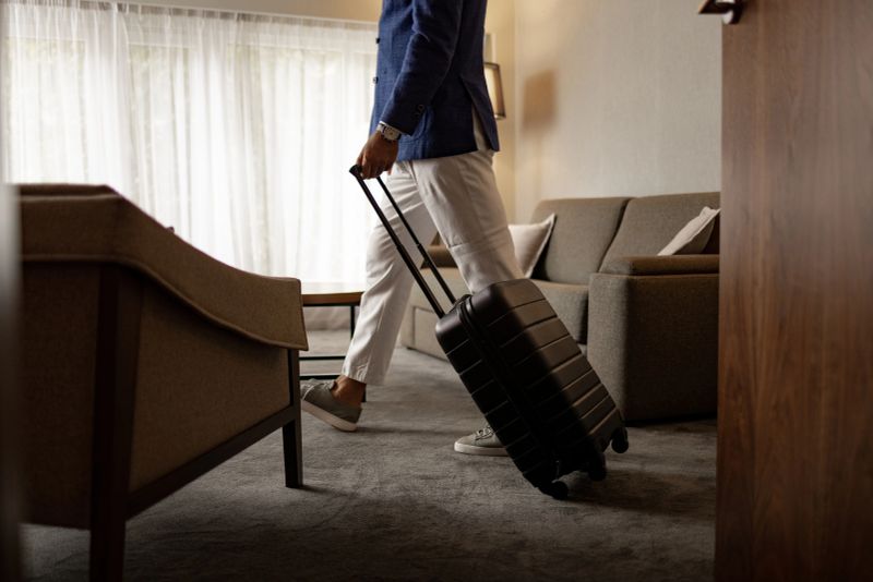 Side view of businessman in smart casual wear with suitcase entering his hotel room