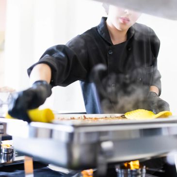 Chef preparando comida em chapa quente.
