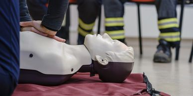 Person practicing CPR on a training mannequin during a safety class.
