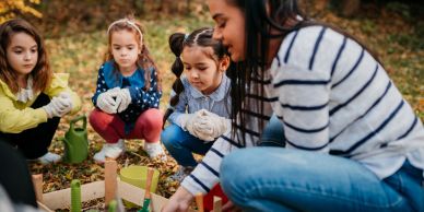 Children planting a garden with adult guidance.