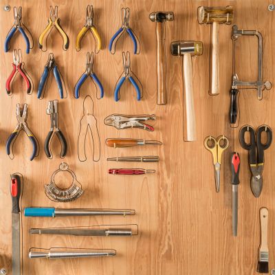 Neatly organized hand tools on a wooden board with outlines for easy placement.