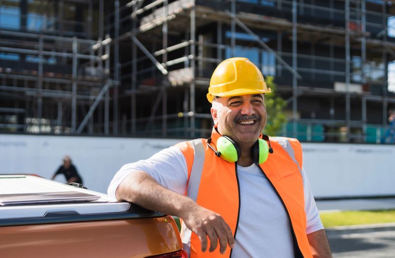 Architect in helmet and safety reflective vest standing at construction site.