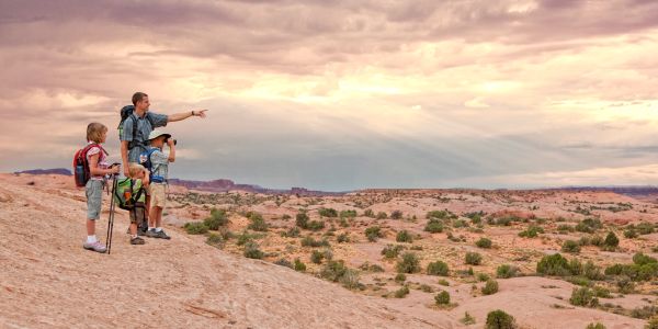 A family hiking in a rocky desert landscape during sunset.