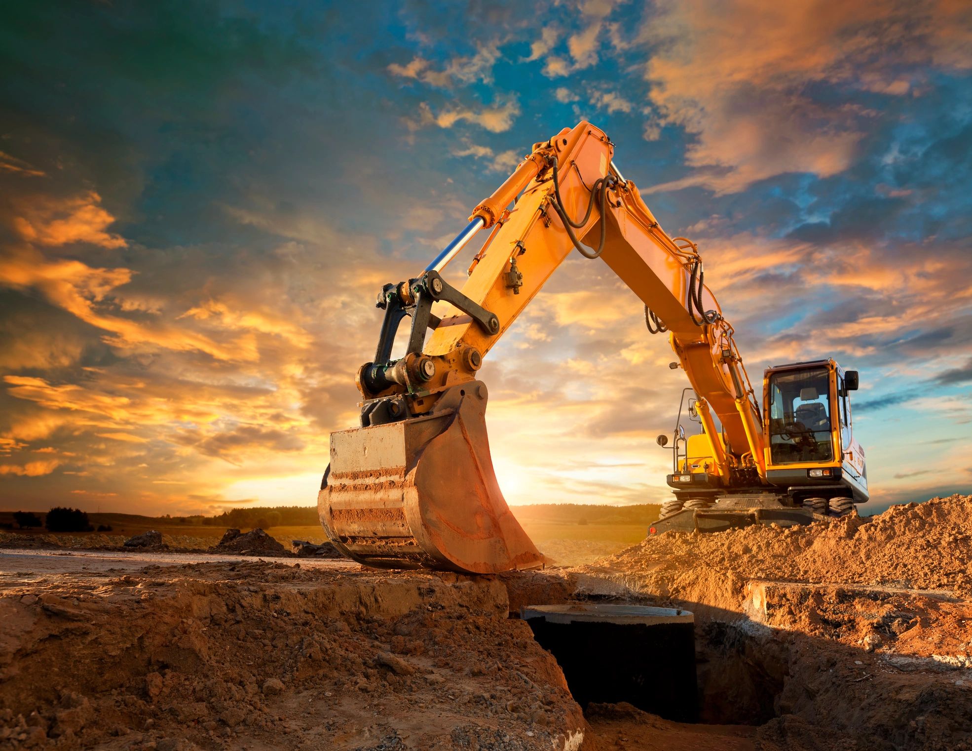Yellow excavator working on muddy construction site with water accumulation.