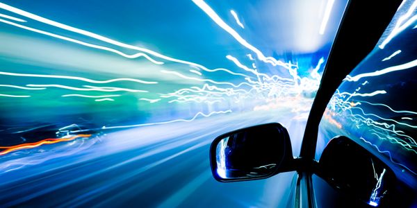 Car speeding at night creating light trails and motion blur.