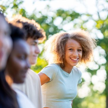 Smiling young woman with curly hair enjoying outdoors with friends.