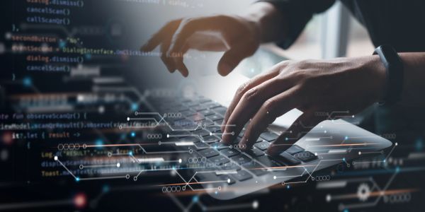Hands typing on a laptop with digital code overlay.