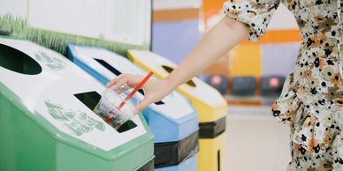 person's arm putting plastic cup into recycling bin