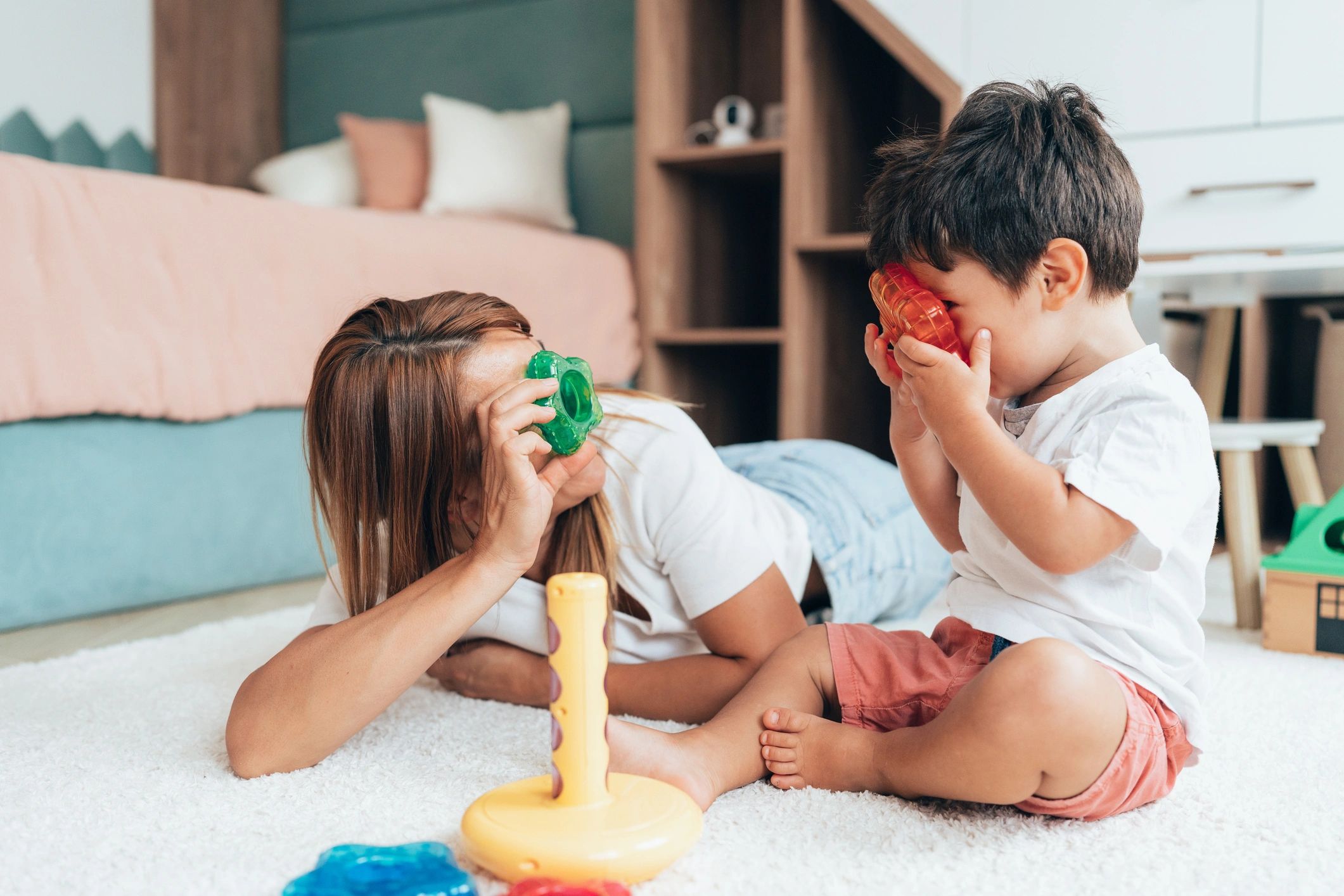 Child and woman playing with colorful toys on the floor.