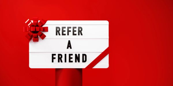 Signboard says 'Refer a Friend' with a red bow on a red background.