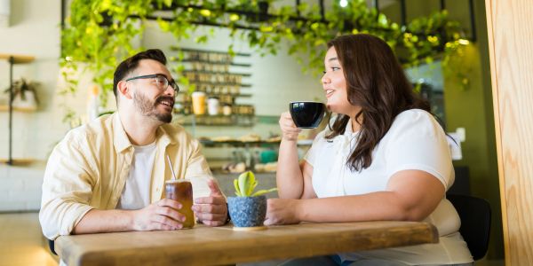Two people chatting and enjoying drinks at a cafe.