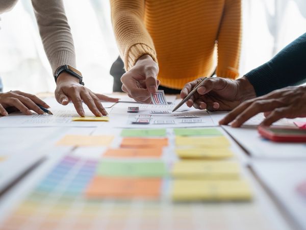 People collaborating on a project with sticky notes and sketches on a table.