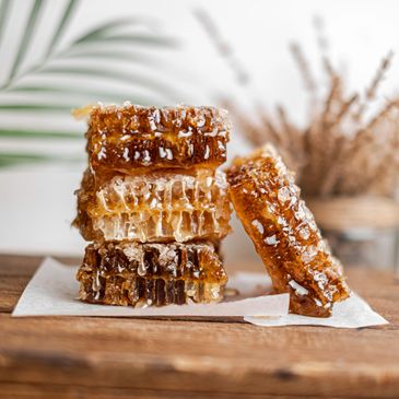 Stacked honeycomb dripping with golden honey on a wooden surface.