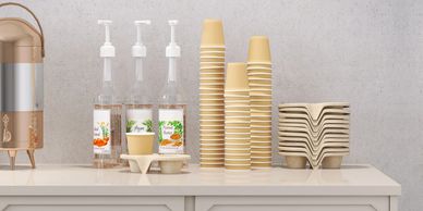 Beverage station with syrup bottles, cups, and lids.