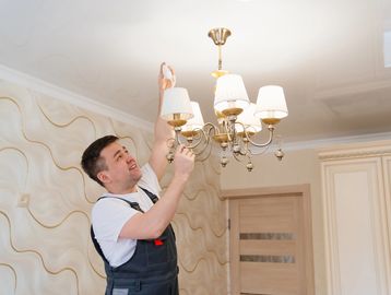 Man fixing chandelier light fixture.