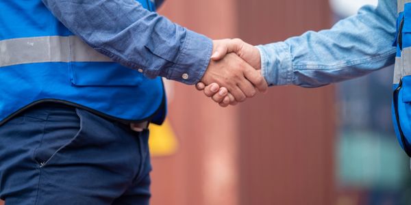 Two workers in blue uniforms shaking hands in agreement.