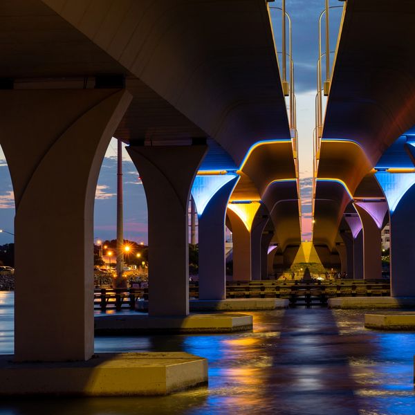 View under a brightly lit bridge at dusk.