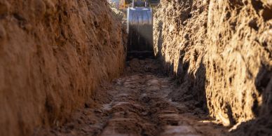 Excavator digging a trench in soil.