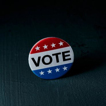 A political vote button with red, white, and blue colors.